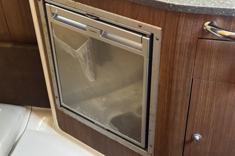 Slide: The Image of Compact refrigerator in 2016 Boston Whaler 315 Conquest boat interior, featuring wood paneling. - 39