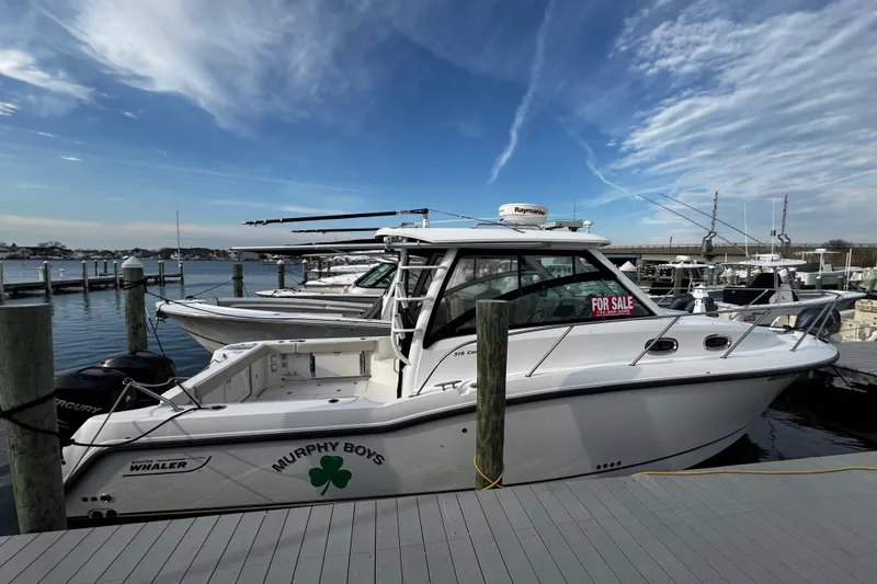 Slide: The Image of 2016 Boston Whaler 315 Conquest boat docked, "For Sale" sign visible, clear sky background. - 4