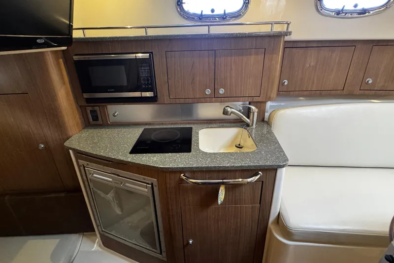 Slide: The Image of 2016 Boston Whaler 315 Conquest galley with microwave, sink, and cooktop. - 42