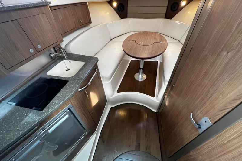 Slide: The Image of 2016 Boston Whaler 315 Conquest cabin interior with kitchenette, seating, and table. - 47