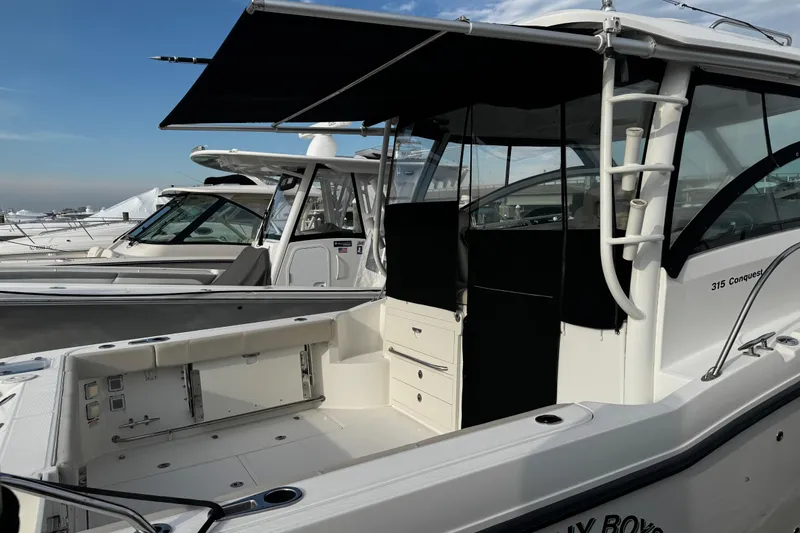Slide: The Image of 2016 Boston Whaler 315 Conquest boat with open deck and canopy, docked at marina. - 5