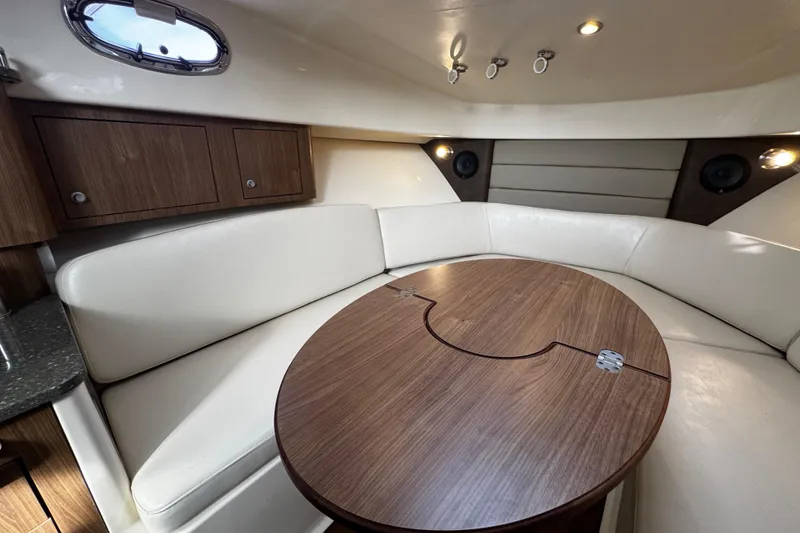 Slide: The Image of 2016 Boston Whaler 315 Conquest cabin interior with wood table and white seating. - 51