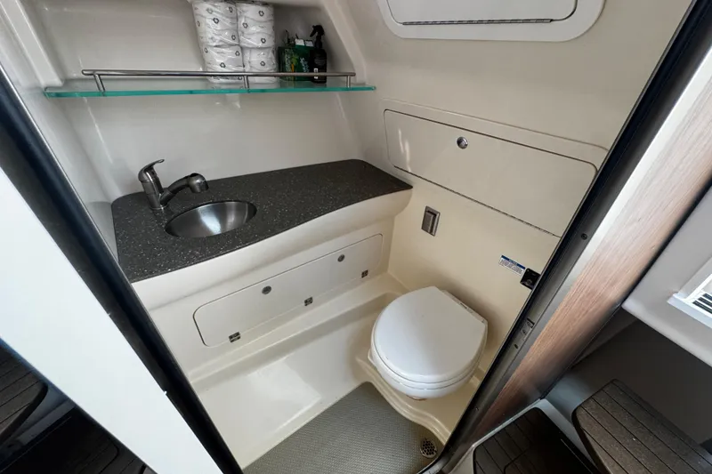 Slide: The Image of 2016 Boston Whaler 315 Conquest bathroom with sink, toilet, and storage shelf. - 55