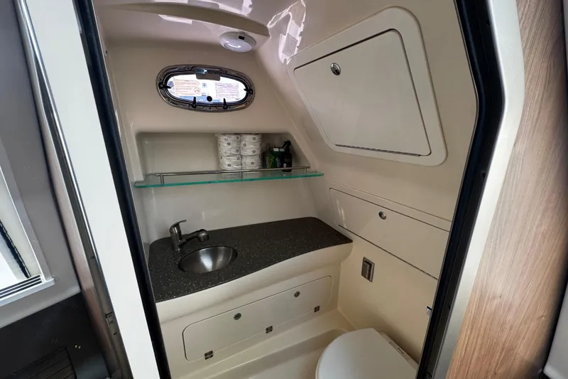 Slide: The Image of 2016 Boston Whaler 315 Conquest bathroom with sink, storage, and porthole window. - 56