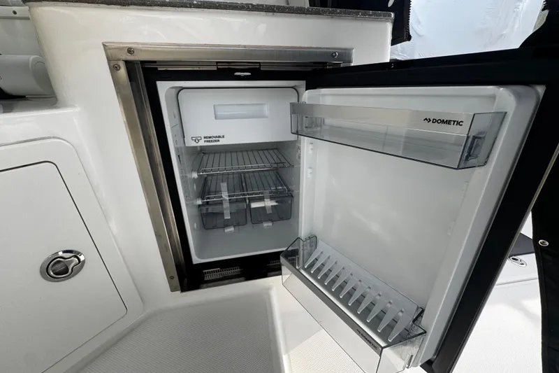 Slide: The Image of Open Dometic refrigerator on 2016 Boston Whaler 315 Conquest boat, showcasing interior storage. - 64