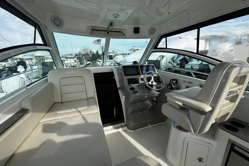 Slide: The Image of Interior of 2016 Boston Whaler 315 Conquest boat, featuring helm and seating area. - 66