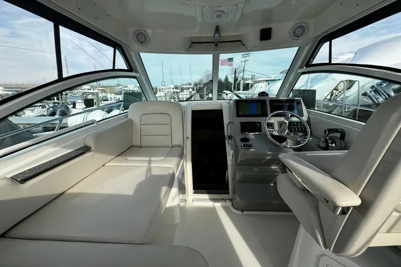 Slide: The Image of Interior of 2016 Boston Whaler 315 Conquest boat, featuring helm and seating area. - 67