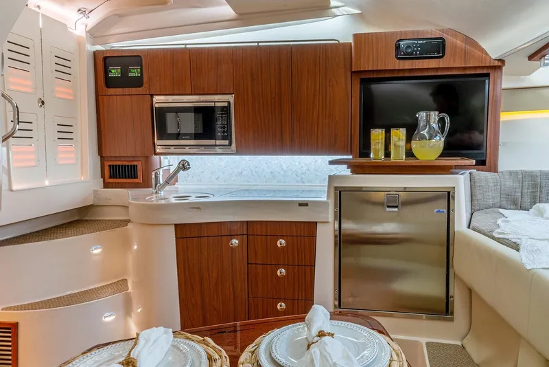 Slide: The Image of Manufacturer Provided Image: 2021 Grady-White Express 330 cabin kitchen with microwave, fridge, and dining setup. - 17