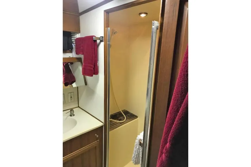 Slide: The Image of 1985 Chris Craft 500 yacht bathroom with shower, sink, and red towels. - 27