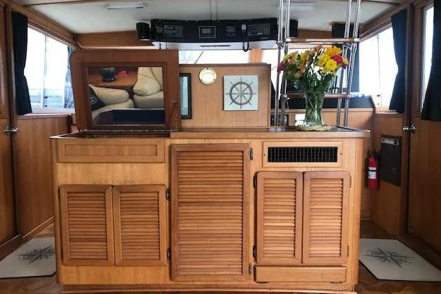 Slide: The Image of 1985 Chris Craft 500 yacht interior with wooden cabinetry and floral arrangement. - 7