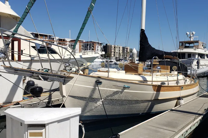 Slide: The Image of 1987 Hans Christian 33 sailboat docked at a marina under clear blue skies. - 2