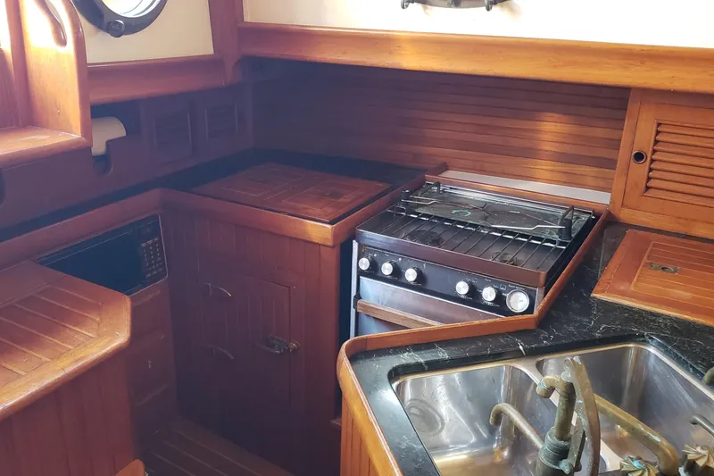 Slide: The Image of 1987 Hans Christian 33 yacht galley with wooden cabinetry, stove, and sink. - 29
