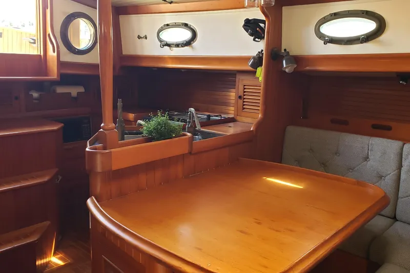 Slide: The Image of Interior of 1987 Hans Christian 33 sailboat with wooden dining area and portholes. - 36