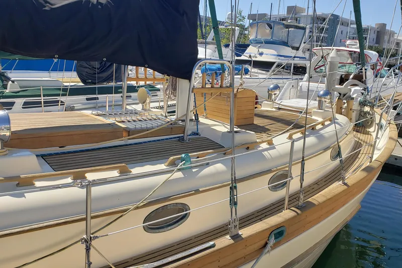 Slide: The Image of 1987 Hans Christian 33 sailboat docked at marina, showcasing classic wooden deck design. - 7