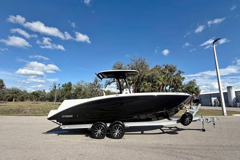 The Image of 2023 Yamaha Boats 255 FSH Sport E on trailer under clear blue sky. - 0