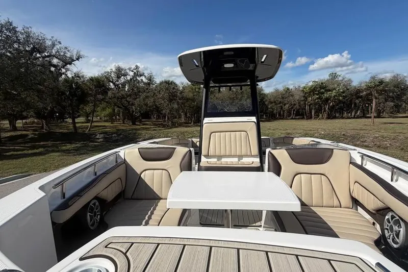 Slide: The Image of 2023 Yamaha Boats 255 FSH Sport E interior with seating and table, surrounded by nature. - 13