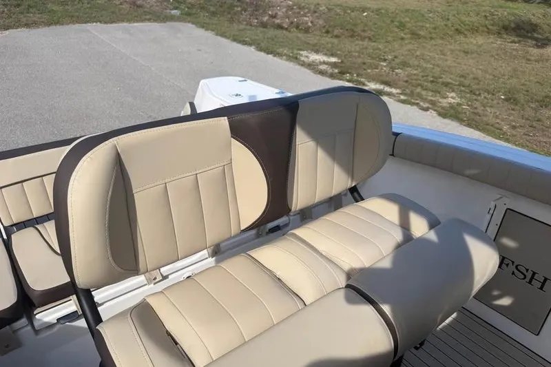 Slide: The Image of 2023 Yamaha Boats 255 FSH Sport E interior seating, featuring beige and brown upholstery. - 15