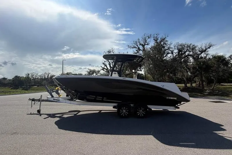 Slide: The Image of 2023 Yamaha Boats 255 FSH Sport E on trailer, parked outdoors under a cloudy sky. - 5