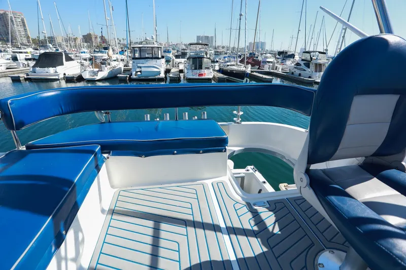 Slide: The Image of 1988 Mediterranean 38 Convertible yacht interior with blue seating, docked at a marina. - 15