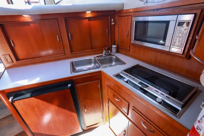 Slide: The Image of 1988 Mediterranean 38 Convertible yacht kitchen with wood cabinets, sink, microwave, and stove. - 37