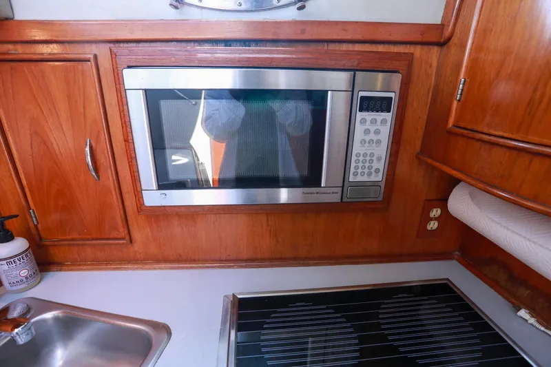 Slide: The Image of 1988 Mediterranean 38 Convertible yacht kitchen with microwave, stove, and wooden cabinetry. - 40