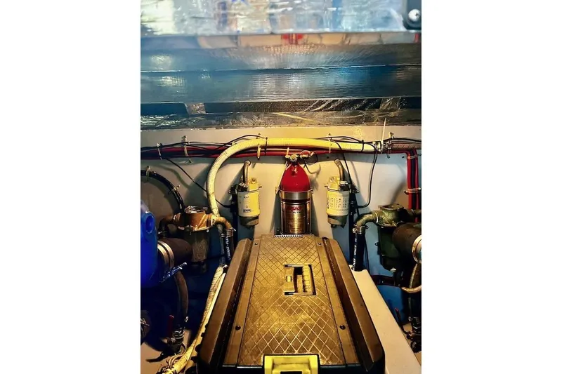 Slide: The Image of Engine room of a 1988 Mediterranean 38 Convertible boat, featuring mechanical components and fire extinguisher. - 60