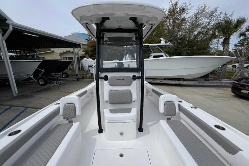 Slide: The Image of 2026 Caymas 26 HB boat interior with seating and console, parked in a marina. - 24