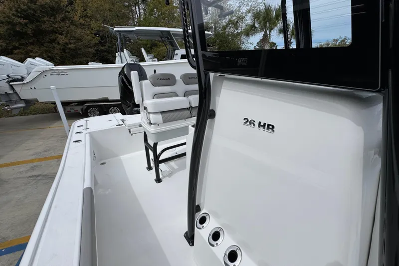 Slide: The Image of 2026 Caymas 26 HB boat with seating and console, parked outdoors. - 26