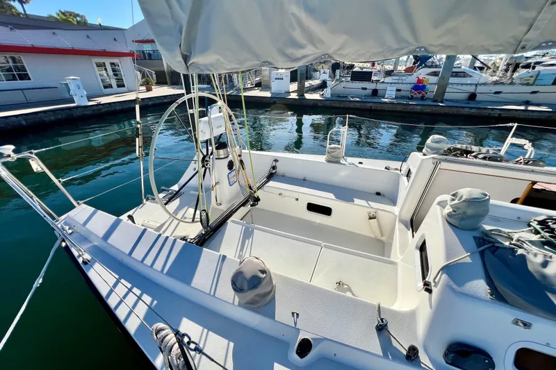 Slide: The Image of 2003 J Boats J/109 sailboat cockpit, docked at marina, showcasing steering wheel and seating area. - 18