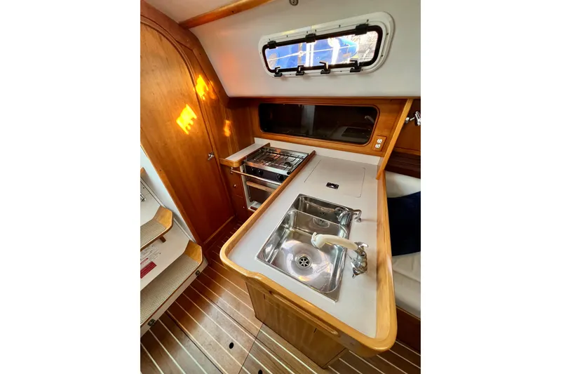 Slide: The Image of 2003 J Boats J/109 yacht interior galley with sink, stove, and wooden cabinetry. - 74