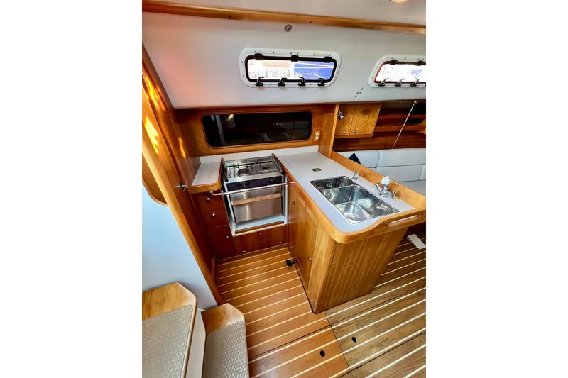 Slide: The Image of Interior of 2003 J Boats J/109 sailboat, featuring a compact wooden galley with stove and sink. - 76
