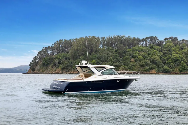 Slide: The Image of 2012 Tiara Yachts 3100 Coronet cruising on a serene lake with lush forest backdrop. - 49