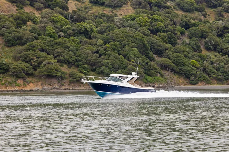 Slide: The Image of 2012 Tiara Yachts 3100 Coronet cruising on a scenic waterway with lush green hills. - 58