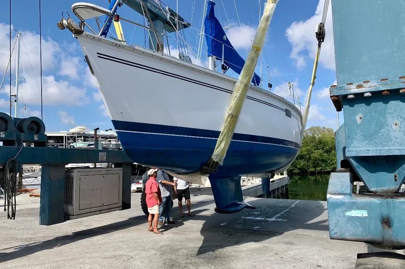Slide: The Image of 1993 Hunter 33.5 sailboat being lifted at a marina with blue skies. - 55