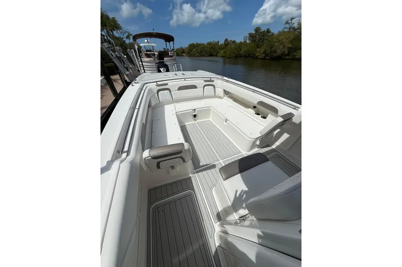 Slide: The Image of 2021 World Cat 280 CC-X boat interior with seating, docked by a scenic river. - 6