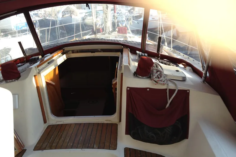 Slide: The Image of Cockpit view of 1989 Gib'Sea 37 sailboat with wooden flooring and red canvas accents. - 11