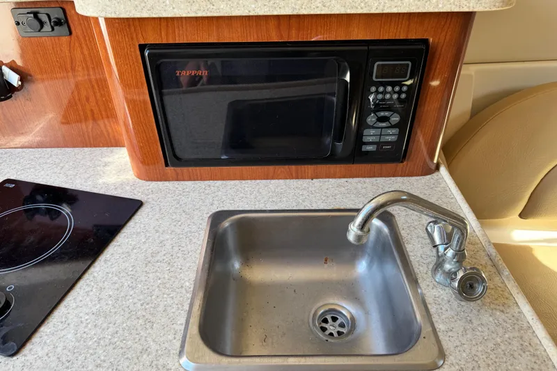 Slide: The Image of Compact kitchen area in a 2007 Regal Commodore 2665 boat with sink and microwave. - 16