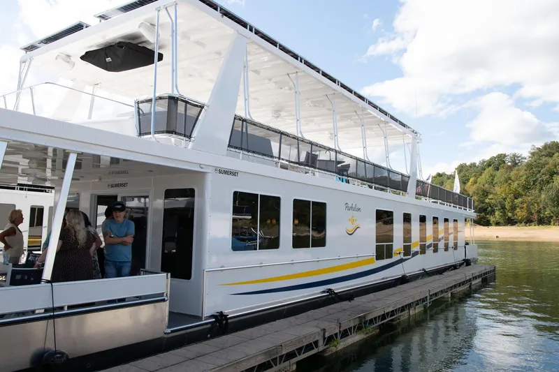 The Image of 2026 Sumerset Luxe II houseboat docked on a serene lake with people onboard. - 1