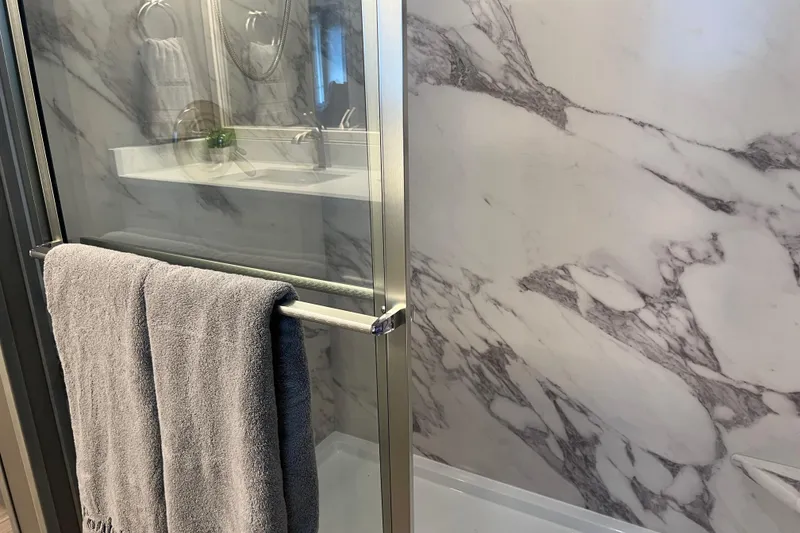 Slide: The Image of Luxurious Sumerset Luxe II 2026 bathroom with marble shower and gray towel. - 35