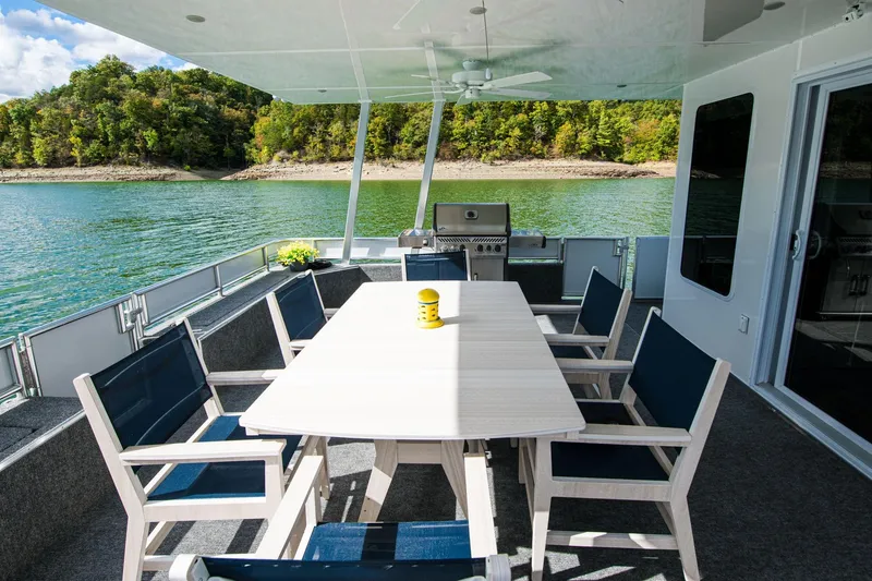 Slide: The Image of Outdoor dining area on 2026 Sumerset Luxe II houseboat, featuring a table, chairs, and scenic lake view. - 36
