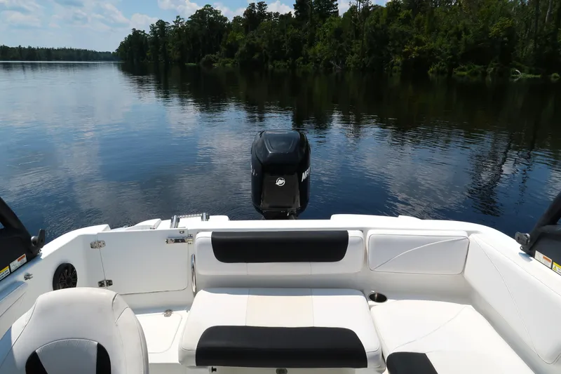 Slide: The Image of 2017 Tahoe 2150 boat interior with seating, on a calm lake with forested shoreline. - 15