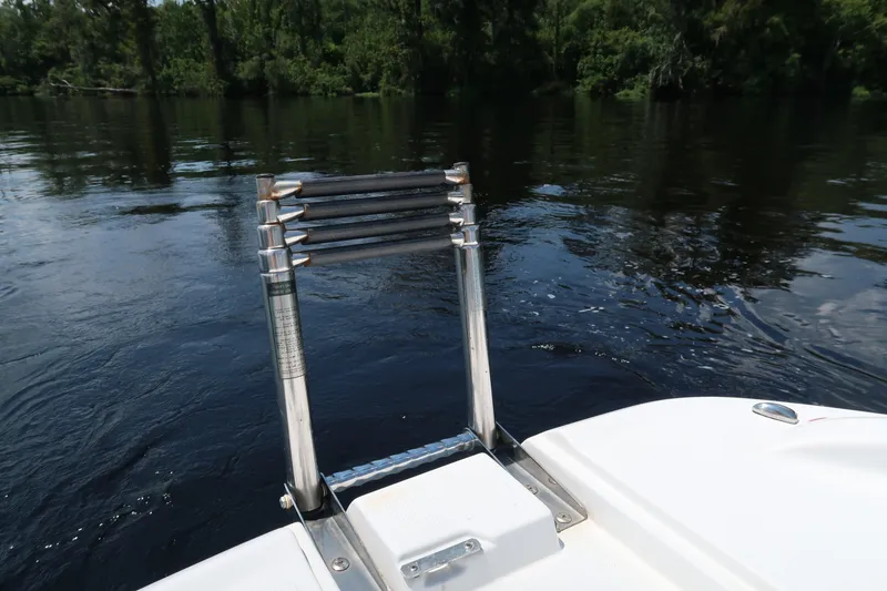 Slide: The Image of 2017 Tahoe 2150 boat ladder on calm water with lush green background. - 6