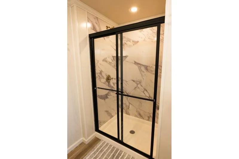 Slide: The Image of Luxurious shower with marble walls and black-framed glass doors in Sumerset Luxe III, 2026 model. - 6