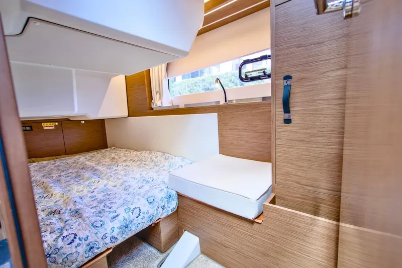 Slide: The Image of 2020 Jeanneau NC 37 cabin interior with bed, wooden finish, and window view. - 24