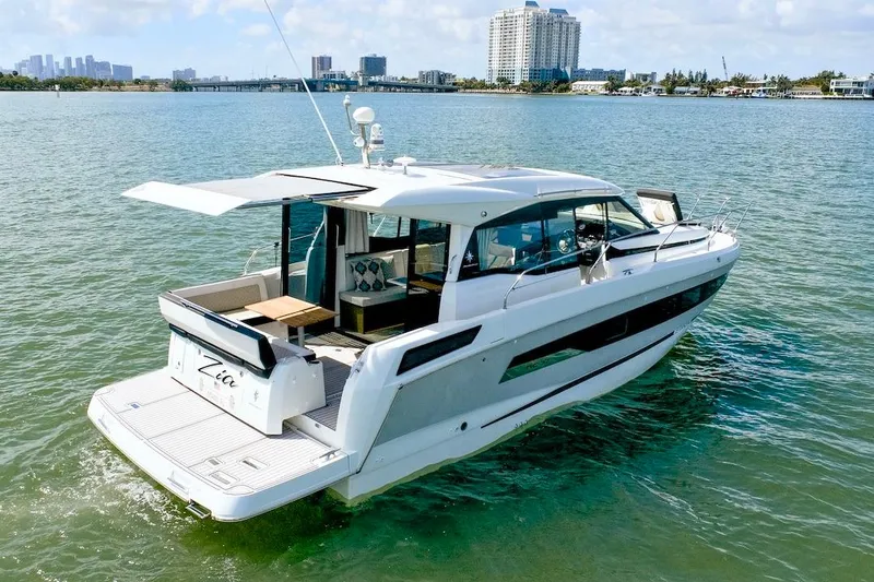 Slide: The Image of 2020 Jeanneau NC 37 yacht cruising on calm waters near a city skyline. - 6