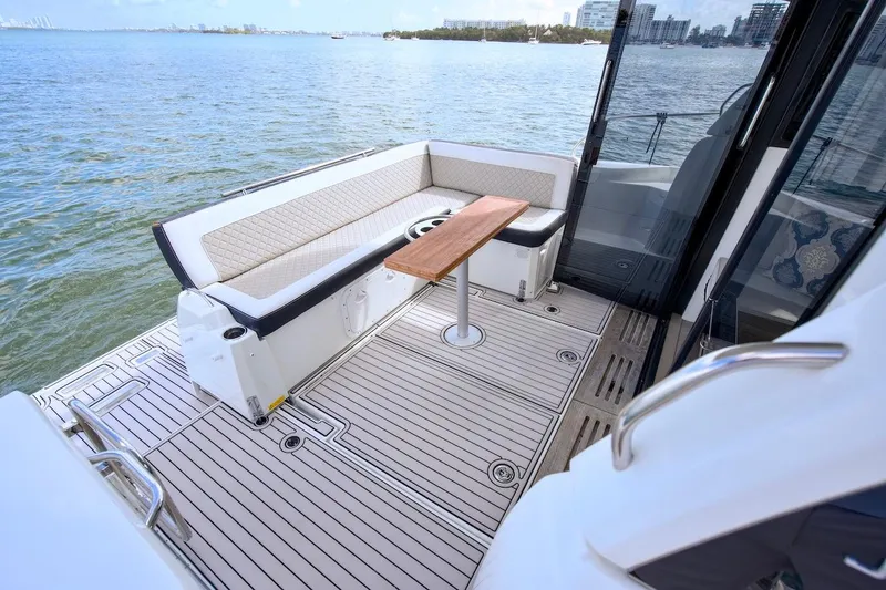 Slide: The Image of 2020 Jeanneau NC 37 boat deck with seating and table, overlooking calm waters. - 9