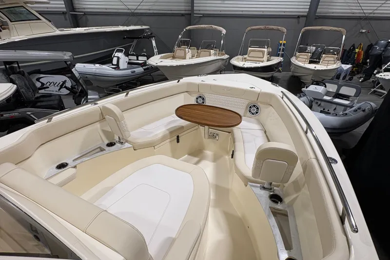 Slide: The Image of 2026 Scout 240 XSF boat interior with seating and table in showroom. - 6