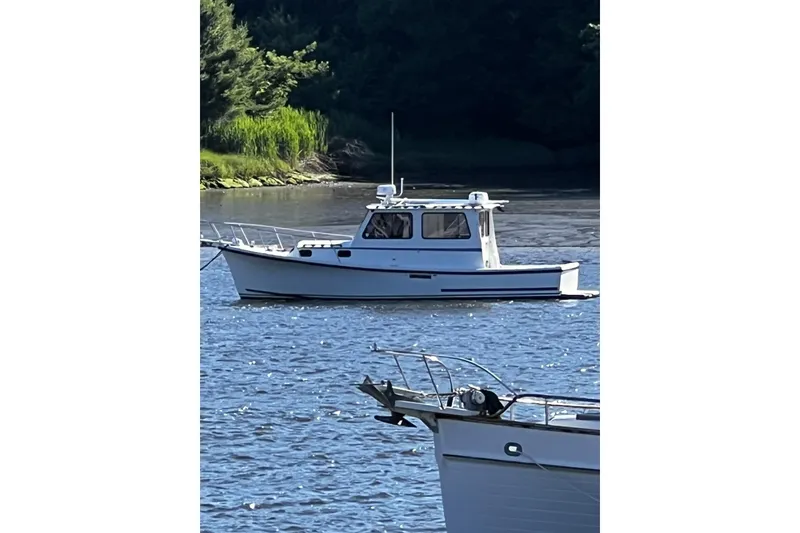 Slide: The Image of 1999 Eastern 31 Casco Bay boat on calm water, surrounded by lush greenery. - 11