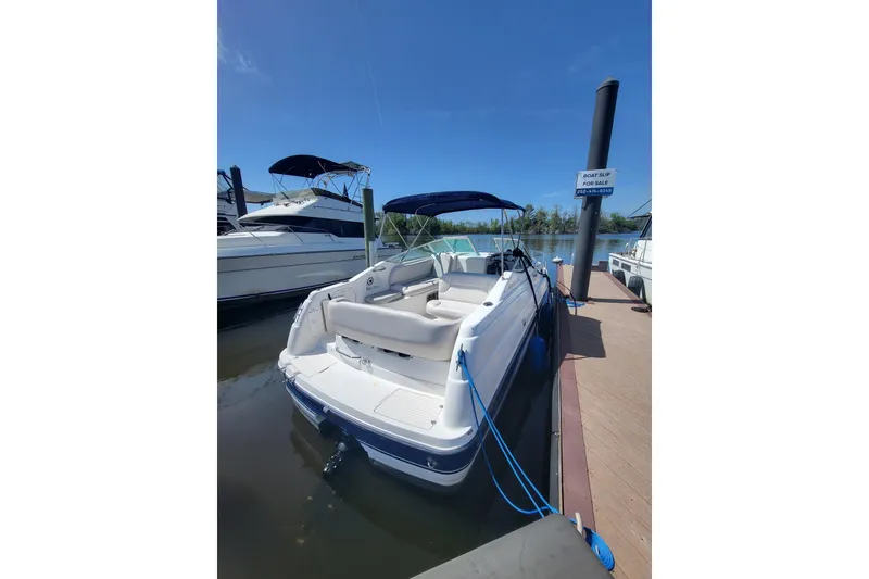 The Image of 1999 Chaparral Signature 240 boat docked, featuring spacious seating and blue canopy. - 0