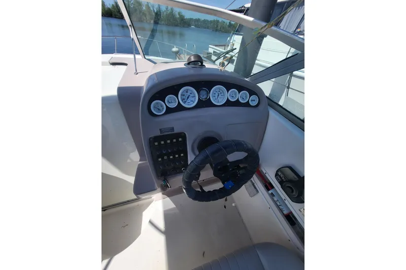 Slide: The Image of 1999 Chaparral Signature 240 boat dashboard with steering wheel and gauges, docked by the water. - 10